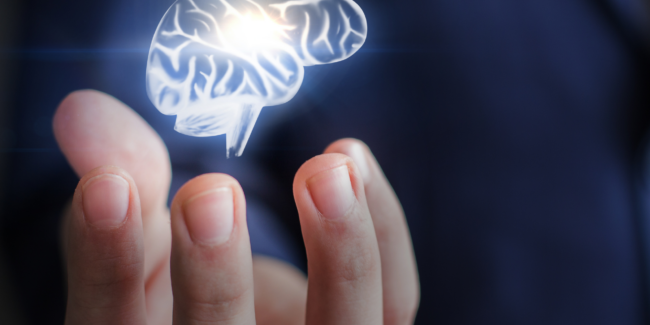 En hånd holder i luften en illustration af en hjernen som lyser
