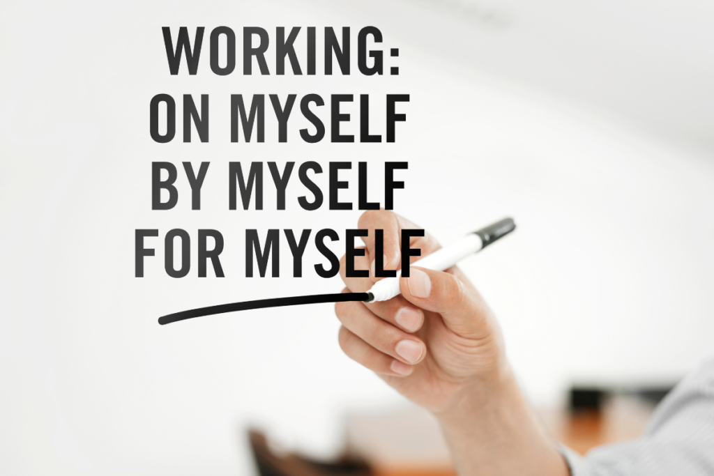 En hånd skriver på en glasrude: Working on myself, by mysef og for myself.